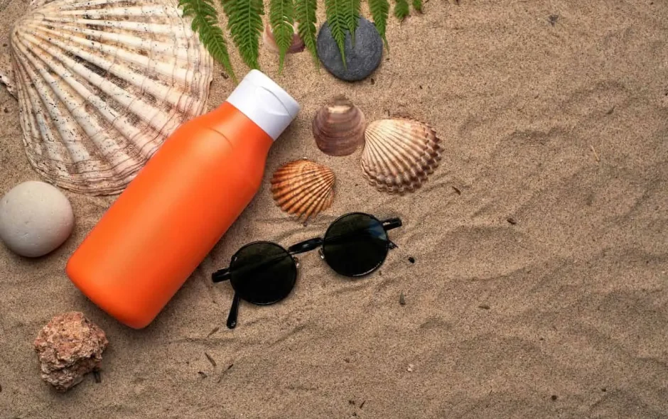 Plage de sable fin avec lunettes de soleil et crème solaire