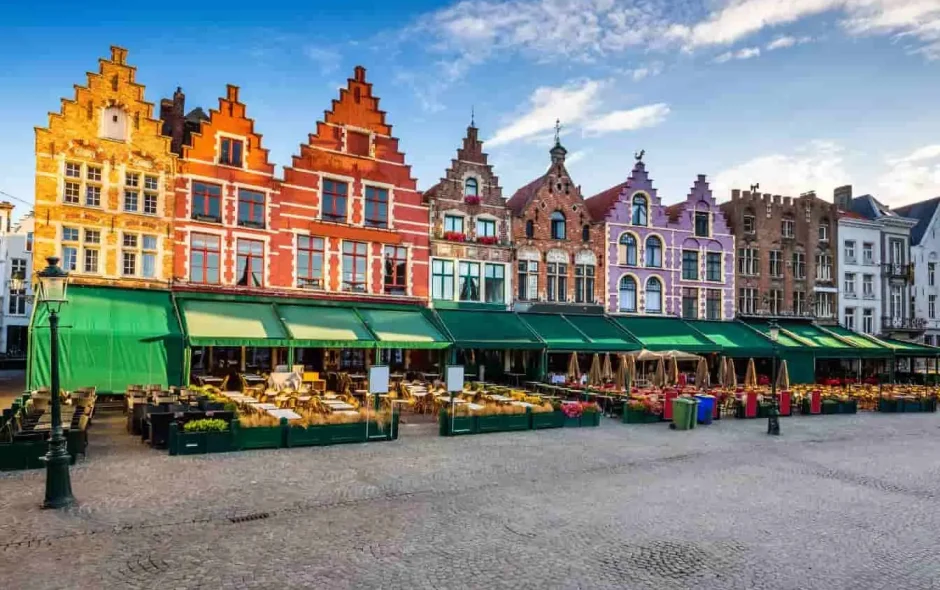 Rangée de maisons flamandes colorées avec pignons à gradins bordant une place pavée calme à Bruges
