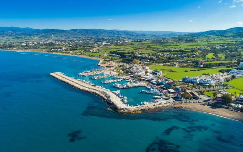Marina bordée de bateaux et ville côtière ensoleillée, image d’un séjour balnéaire à Chypre