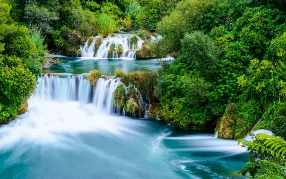 Eau fluide descendant sur roches entourées de végétation dense, image liée à une exploration du parc de Krka