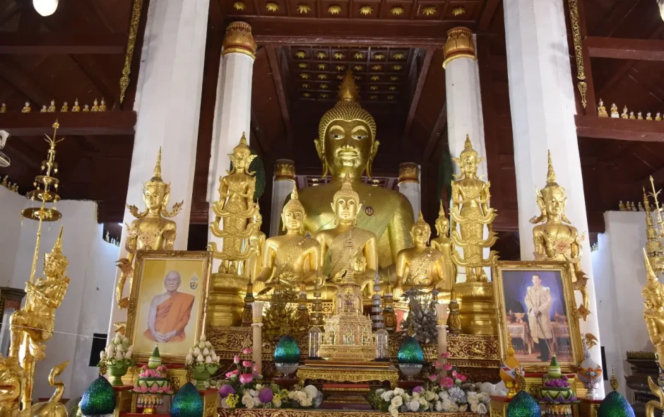 Grand Bouddha doré entouré de statues, image illustrant les traditions religieuses en Thaïlande et la richesse des temples bouddhistes.