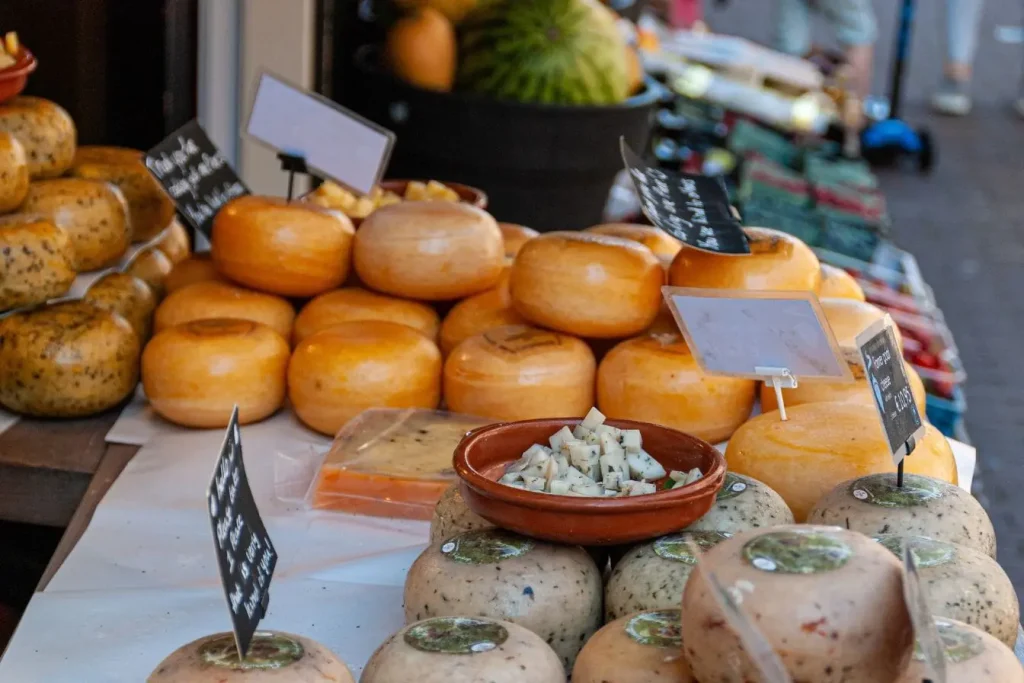 Étals de marché remplis de meules de fromages variés, rappelant les spécialités culinaires belges et leur tradition artisanale de produits laitiers.