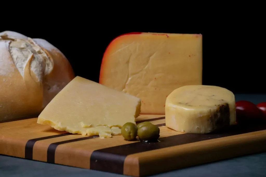 Plateau en bois garni de fromages variés, pain rustique, olives vertes et tomates cerises illustrant une spécialité bretonne gourmande