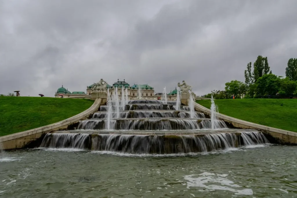 Fontaine monumentale avec cascades d’eau devant palais baroque de Vienne, image illustrant l’élégance architecturale et culturelle autrichienne