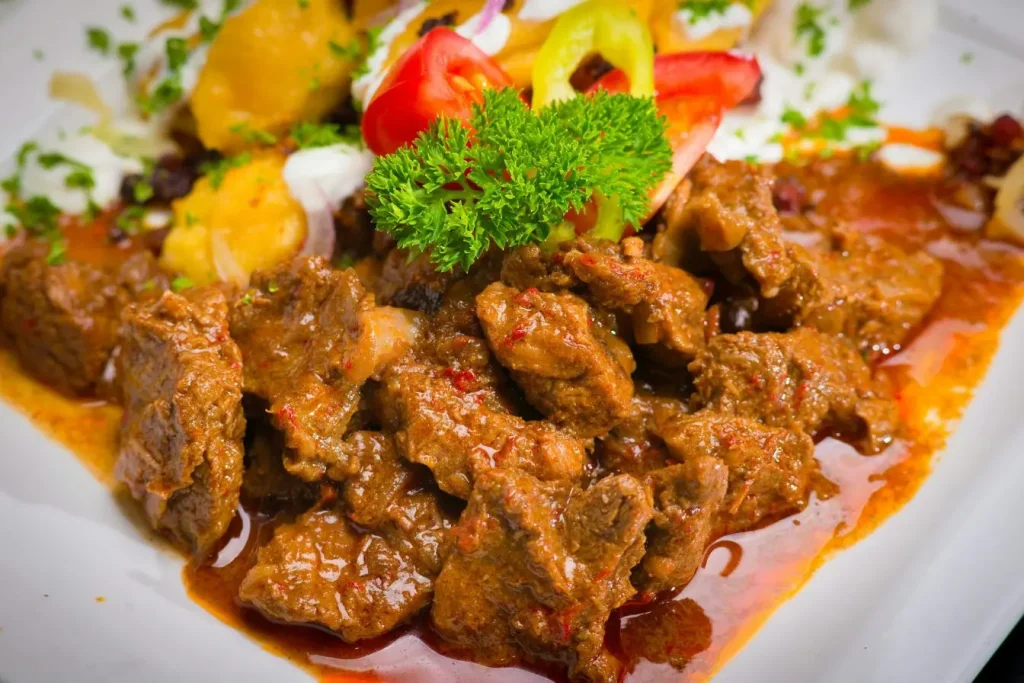 Assiette de ragoût de bœuf en sauce riche avec pommes de terre et légumes, rappelant les spécialités culinaires belges comme le stoofvlees.