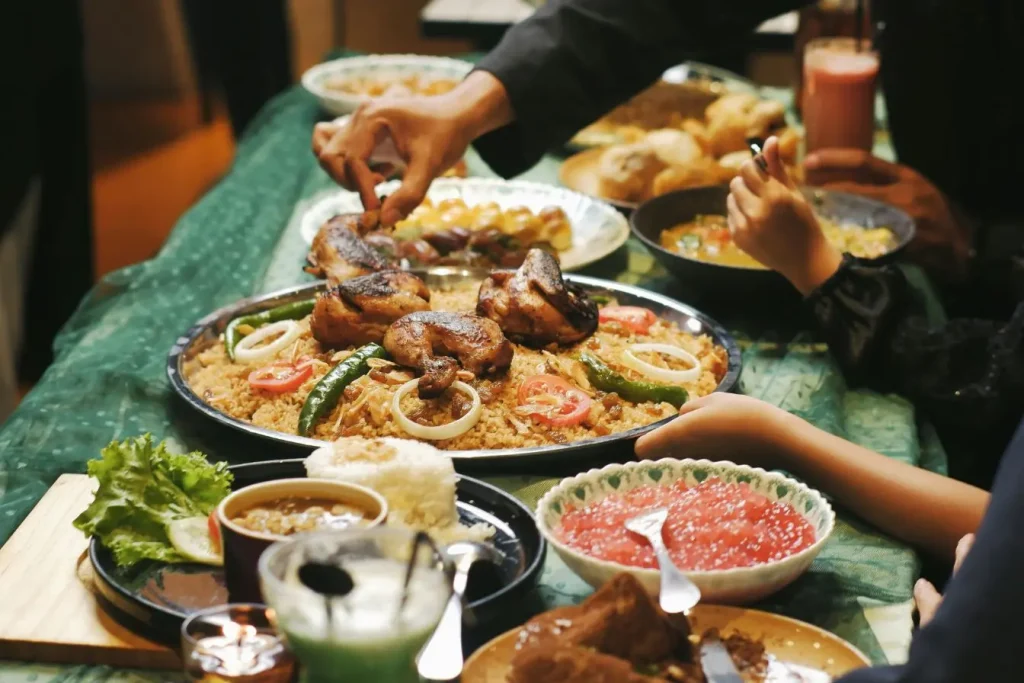 Repas festif avec poulet grillé et légumes, image représentant les traditions religieuses en Thaïlande et les offrandes culinaires.