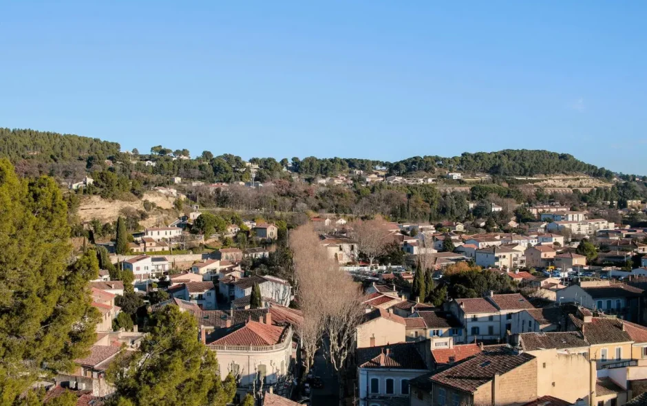 Vue pittoresque d’un village provençal avec toits rouges et collines boisées, image illustrant le charme authentique des villages de Provence.