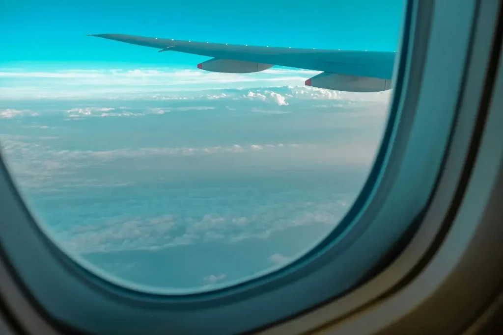 Vue aérienne depuis hublot avec ciel clair, image représentant la recherche de vols pas chers et l’optimisation du budget.