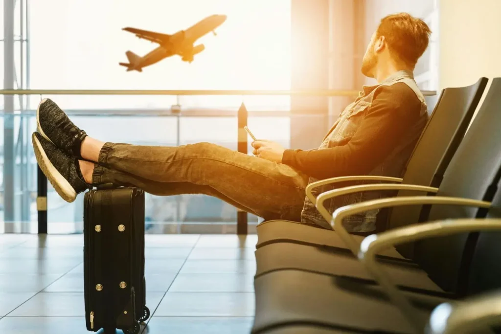 Voyageur assis en terminal avec valise noire et smartphone