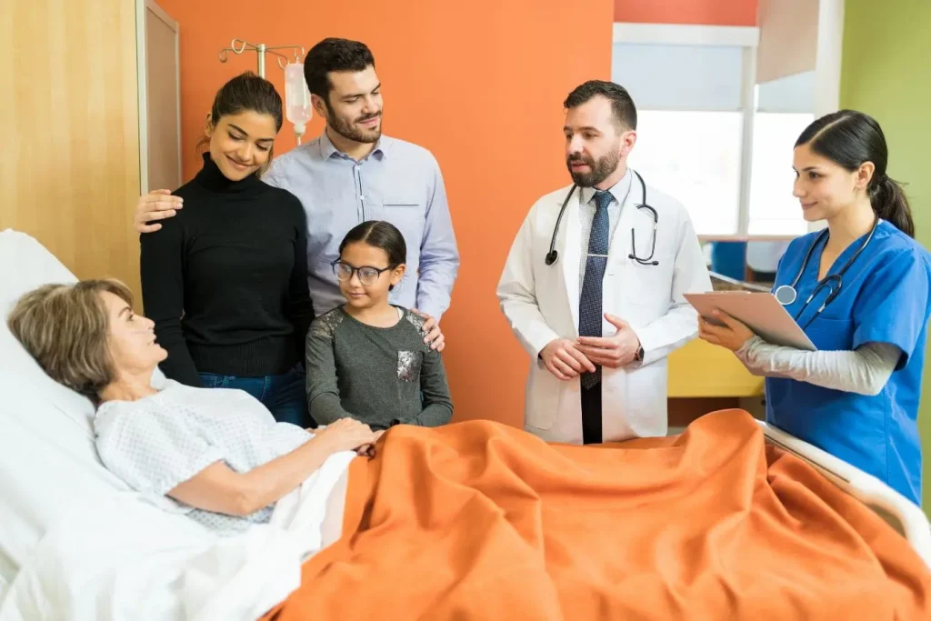 Chambre d’hôpital avec patient âgé entouré de famille et médecins, image d’un voyage où l’assurance choisie protège santé et imprévus.