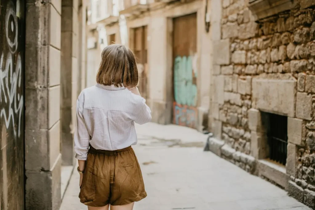 Femme seule avançant dans ruelle étroite aux murs de pierre, image illustrant le voyage en solo femme dans un quartier historique.