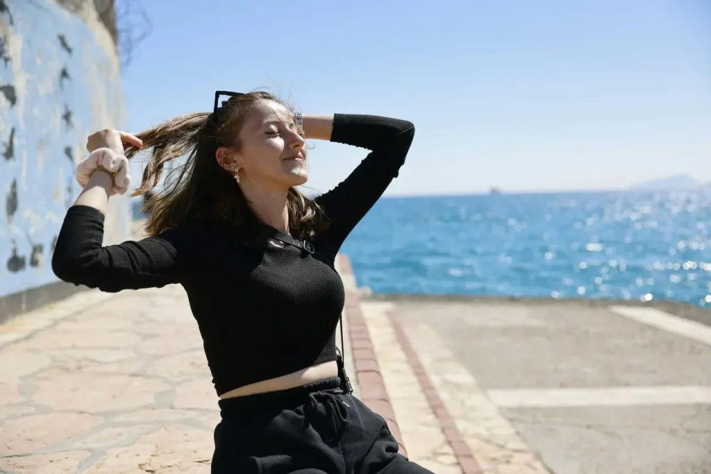Voyageuse en haut noir profitant du ciel bleu, symbole de l’indépendance et du voyage en solo femme.