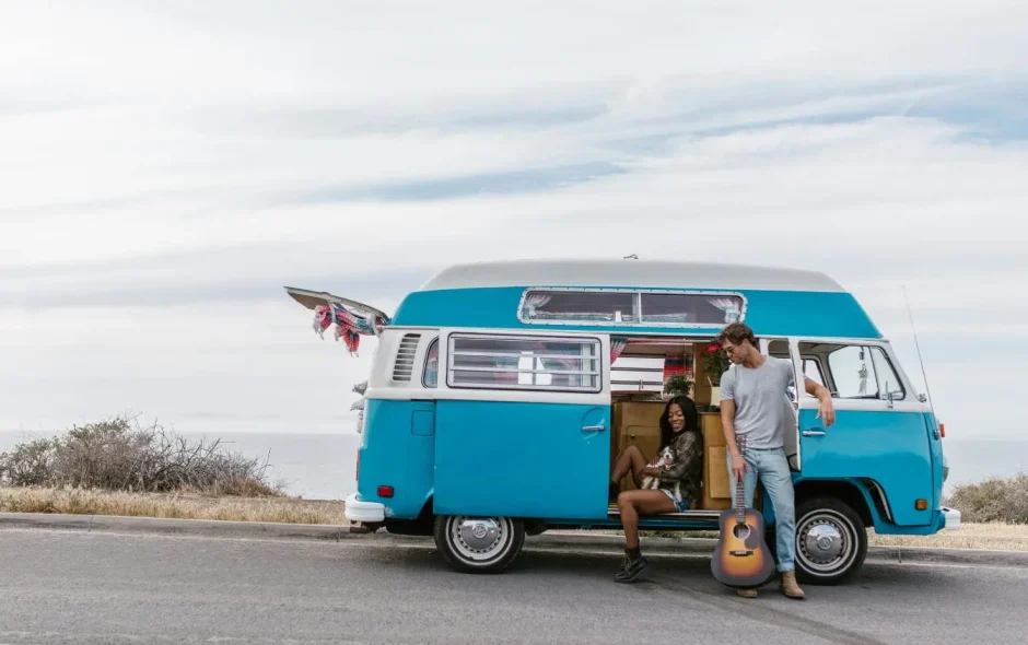 Van vintage bleu et blanc garé au bord de mer, image illustrant le voyage en van aménagé et la liberté de vivre la route.