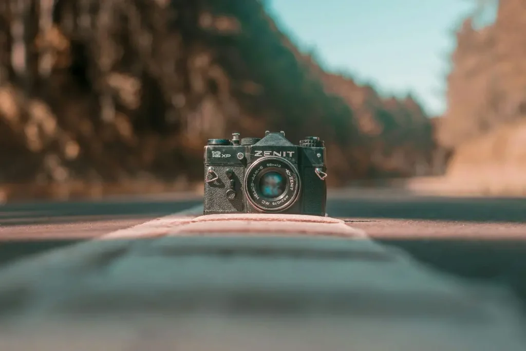 Gros plan sur boîtier argentique centré sur chaussée, scène évoquant la réflexion pour choisir son appareil photo de voyage.