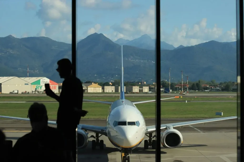 Avion stationné sur piste vu depuis terminal vitré, image illustrant les droits des passagers en cas d’annulation de vol.