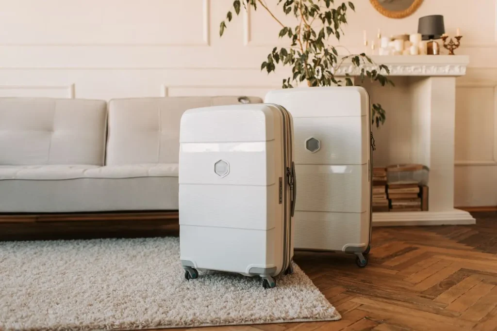 Deux valises blanches rigides posées sur tapis clair dans salon élégant, image illustrant la meilleure valise cabine pour voyager souvent avec confort.