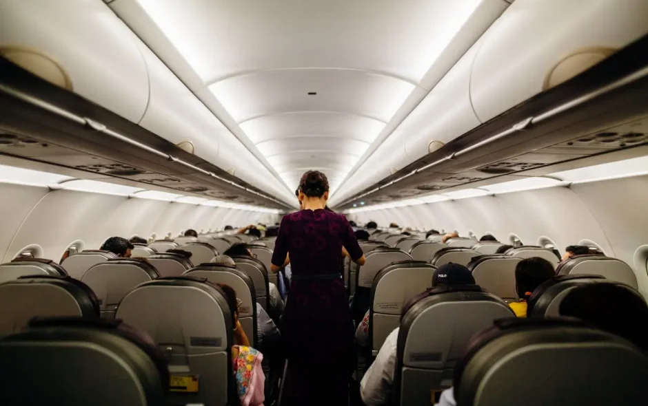 Cabine d’avion avec passagers assis et hôtesse, image illustrant l’importance de gestes simples pour éviter le mal des transports en vol.