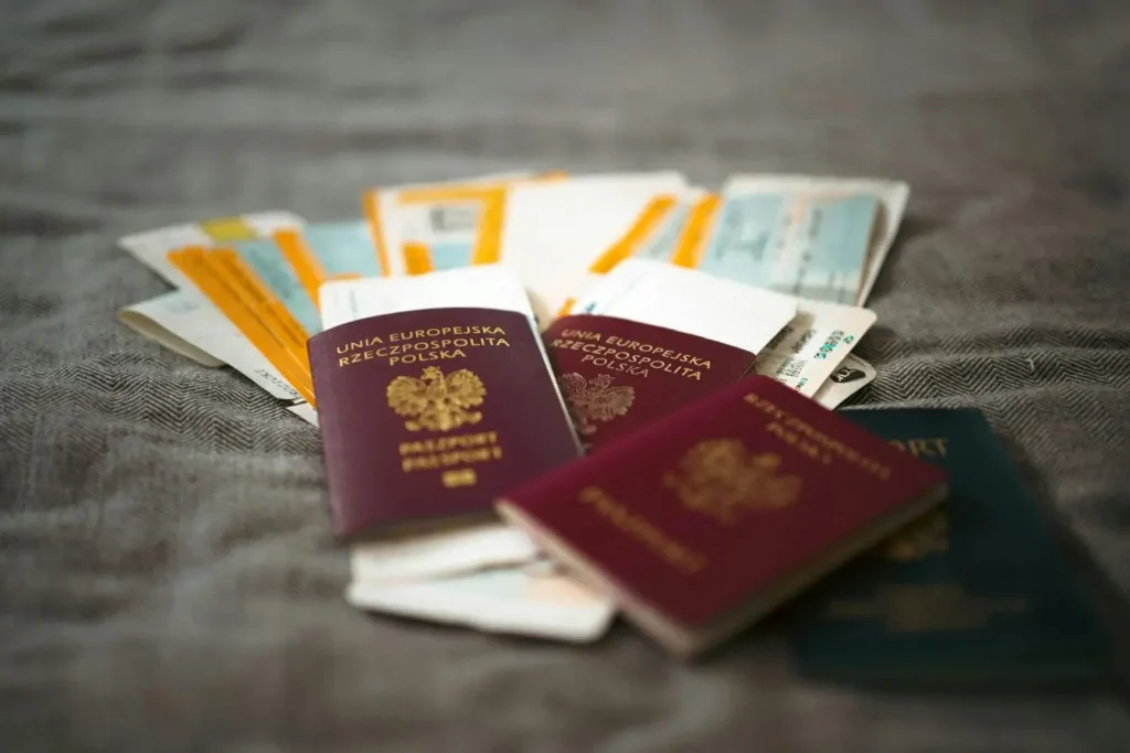 Passeports colorés posés sur surface texturée avec billets d’avion, image illustrant la préparation d’un tour du monde.