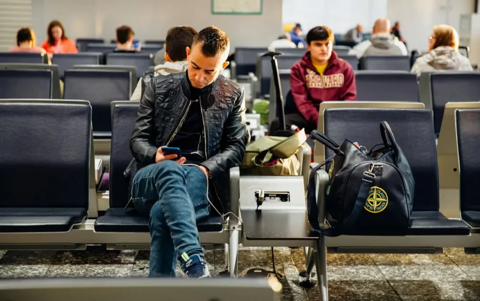 Salle d’attente lumineuse avec sièges bleus occupés, reflet des critères essentiels des droits des passagers en cas d’annulation de vol.