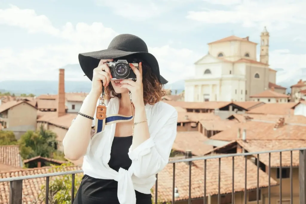 Personne en chapeau noir photographiant depuis balcon, image illustrant le choix d’un appareil photo pour voyager.