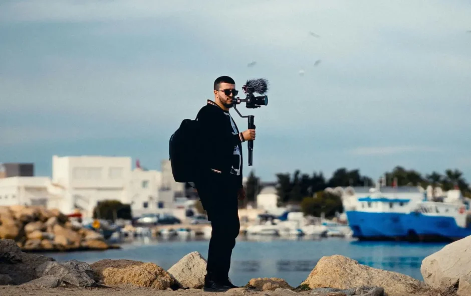 Un vidéaste équipé d'un stabilisateur et d'un micro filme un port maritime pour capturer l'essence de ses aventures et partager ses récits de voyage en ligne