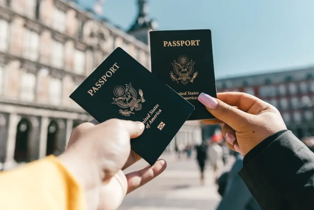 Deux mains tenant des passeports américains bleus, image évoquant le risque de vol à l’étranger et les démarches urgentes pour rentrer.