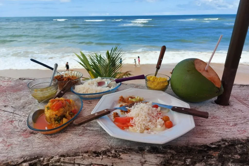 Table rustique avec plats traditionnels et vue sur mer, symbole des adresses locales authentiques à privilégier.