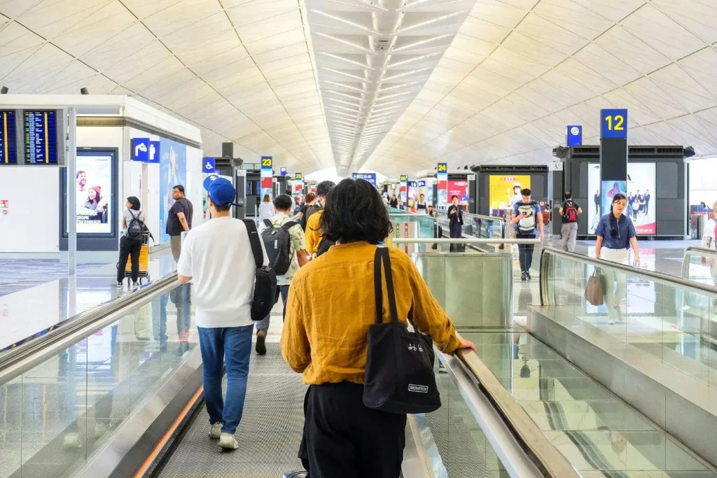 Passagers avançant sur tapis roulants vers leurs portes, symbole des pratiques liées aux droits des passagers en cas d’annulation de vol.