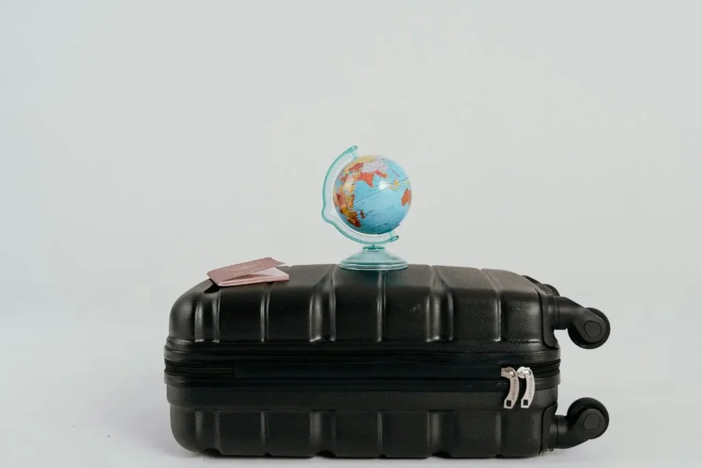 Globe posé sur valise noire avec passeports visibles, image illustrant la préparation d’un tour du monde.