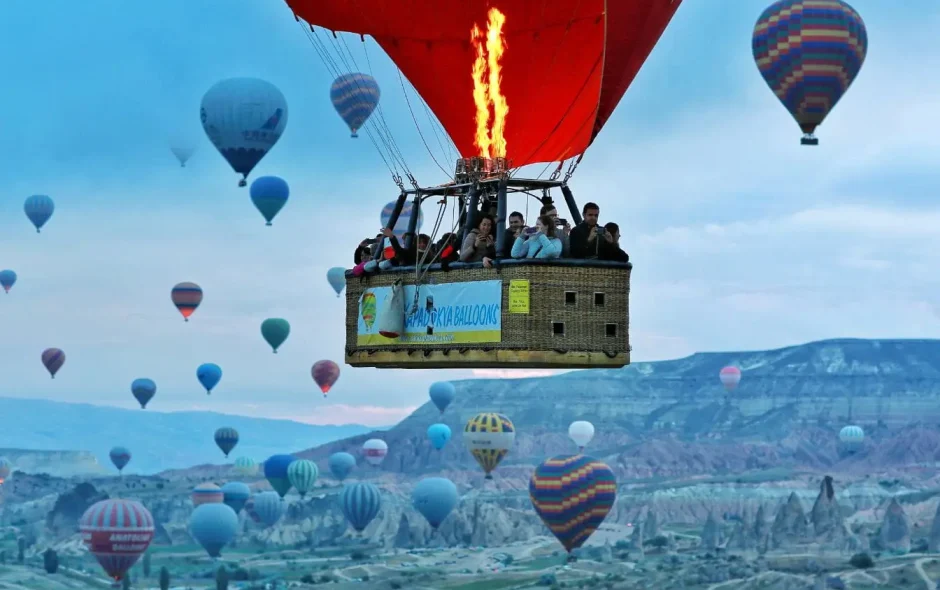 Ciel rempli de montgolfières colorées au-dessus de formations rocheuses, image illustrant la magie de visiter la Cappadoce.