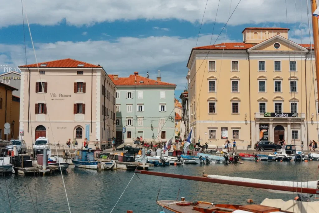 Port pittoresque avec bateaux amarrés devant façades colorées, image qui illustre le charme méditerranéen de Piran en Slovénie.