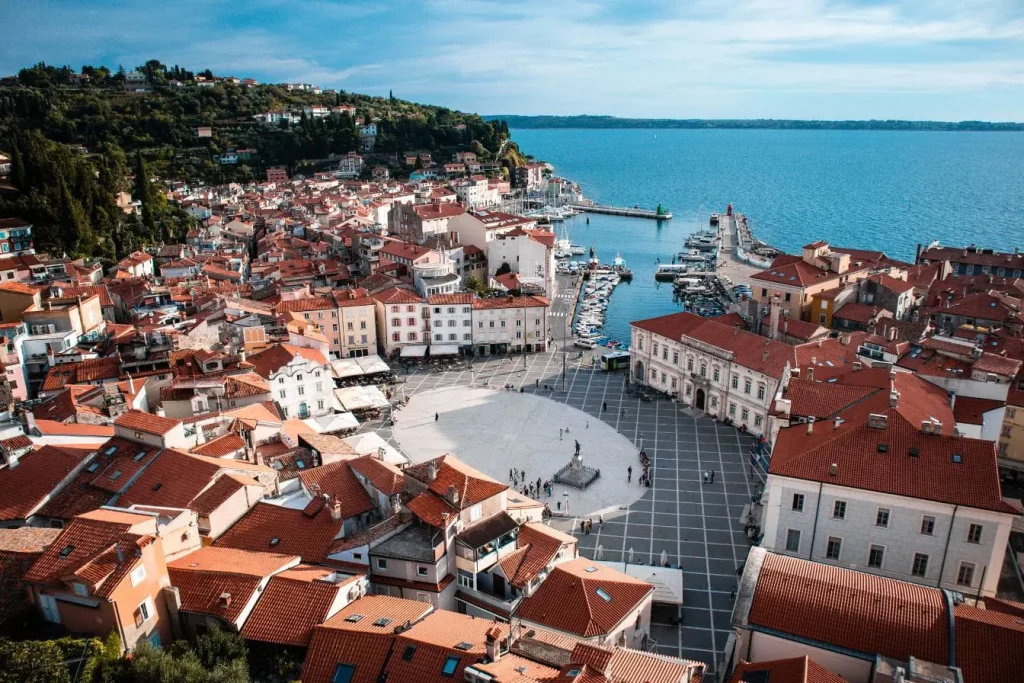 Place circulaire bordée de maisons pastel et statue centrale, reflet de l’ambiance pittoresque de Piran en Slovénie.