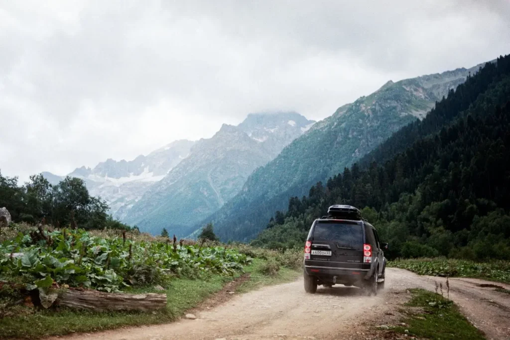 Voiture équipée d’un coffre de toit avançant sur route de terre, reflet de l’esprit d’exploration d’un road trip en Géorgie.