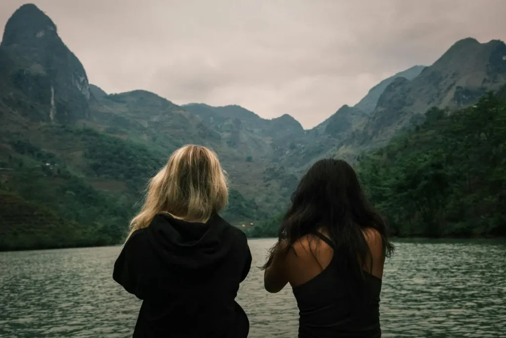 Deux personnes assises au bord de l’eau face aux montagnes verdoyantes, image qui illustre la sérénité d’un séjour au Monténégro en une semaine