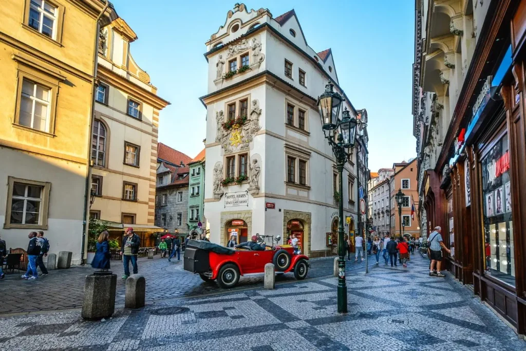 Voiture vintage rouge stationnée devant bâtiment orné, illustration typique d’Olomouc à découvrir.