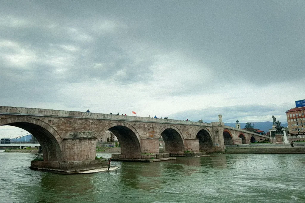 Pont de pierre ancien aux arches majestueuses traversant une rivière, image qui illustre le charme historique à découvrir en visitant Skopje.