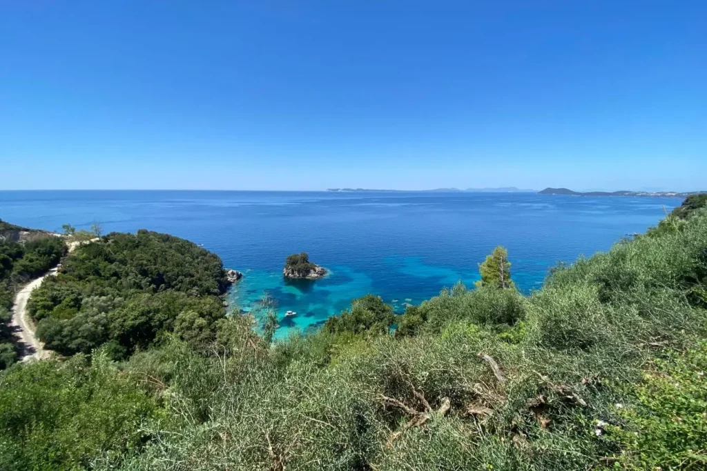 Paysage côtier verdoyant avec route sinueuse longeant mer turquoise, reflet des trésors cachés et incontournables de l’Épire en Grèce.