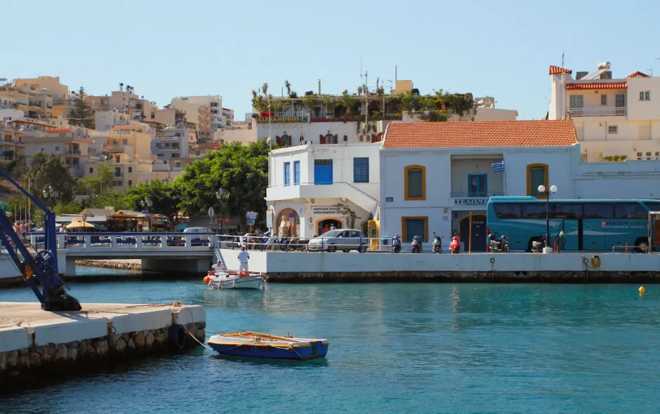 Port ensoleillé avec bateaux et bus bleu, image qui illustre l’ambiance méditerranéenne et l’envie de visiter Héraklion.
