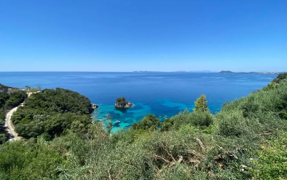 Paysage côtier verdoyant avec route sinueuse longeant mer turquoise, reflet de la beauté naturelle d’Ioannina, perle de l’Épire.