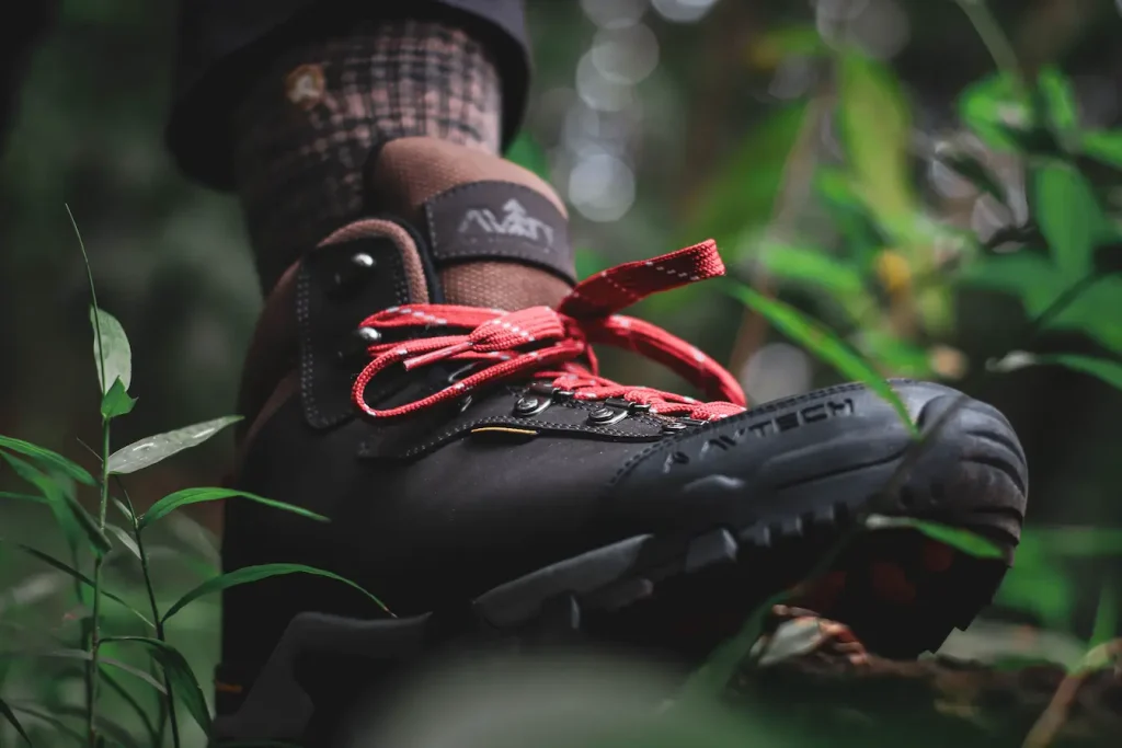 Gros plan sur chaussure de randonnée noire et marron avec lacets rouges, image qui illustre l’importance de bien choisir ses chaussures de randonnée.