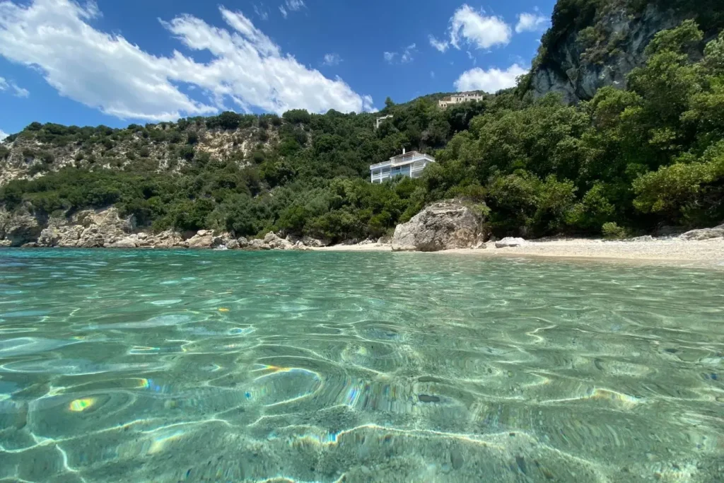 Plage de sable bordée de rochers et mer turquoise, reflet des paysages enchanteurs d’Ioannina, perle de l’Épire.
