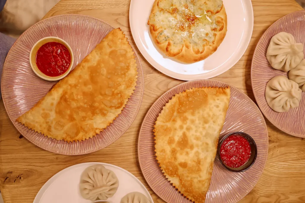 Chebureki croustillants servis avec sauce rouge, illustration des spécialités culinaires géorgiennes.