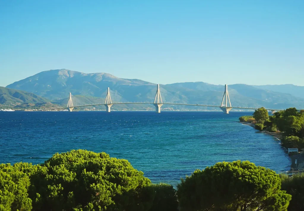 Pont moderne suspendu au-dessus de l’eau bleue, image qui invite à visiter Patras et découvrir son impressionnante architecture.
