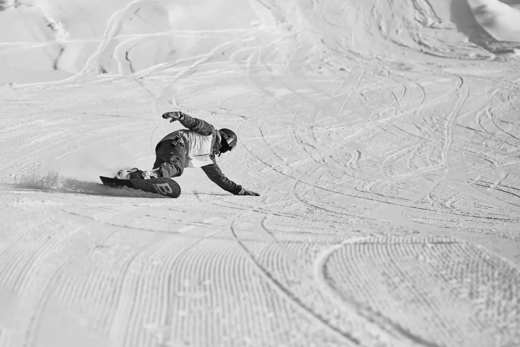 Snowboardeur réalisant un virage engagé sur une vaste pente enneigée, une image qui évoque les meilleures stations pour le snowboard freeride en montagne